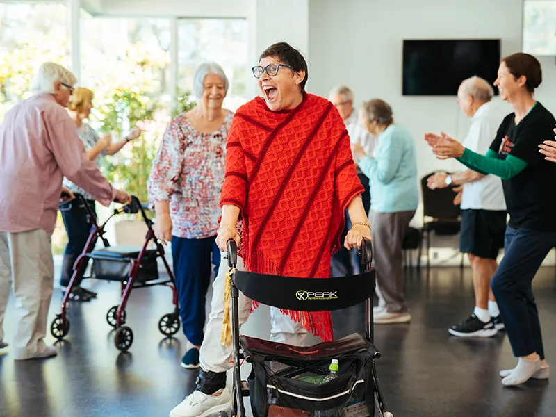 Women in bright red shawl laughing while dancing with walker