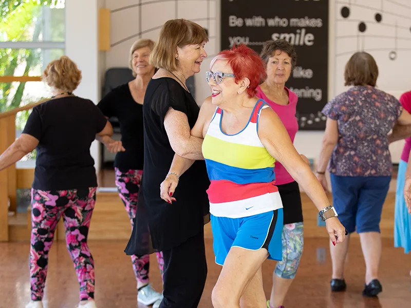 Smiling older woman wearing bright colourful clothing dancing with a partner