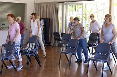 Elderly people using chairs as dance props