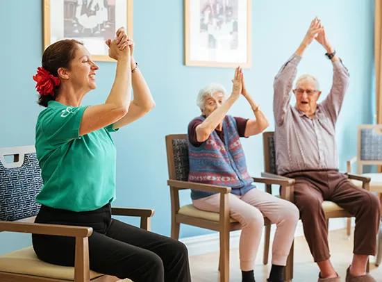 Instructor showing elderly couple simple dance moves while seated