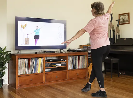 Women dancing in front of tv while watching instructional video