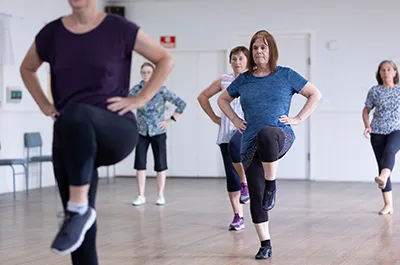 Elderly women in dance studio kicking their legs up