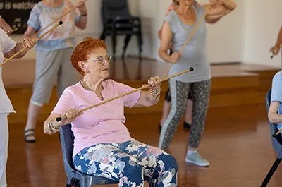 Elderly woman sitting in chair with cane doing dance move