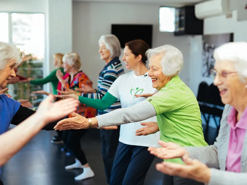 Elderly women standing in a line having fun, smiling abd dancing with each other